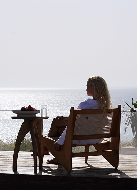 A woman seated on a terrace overlooking the sea